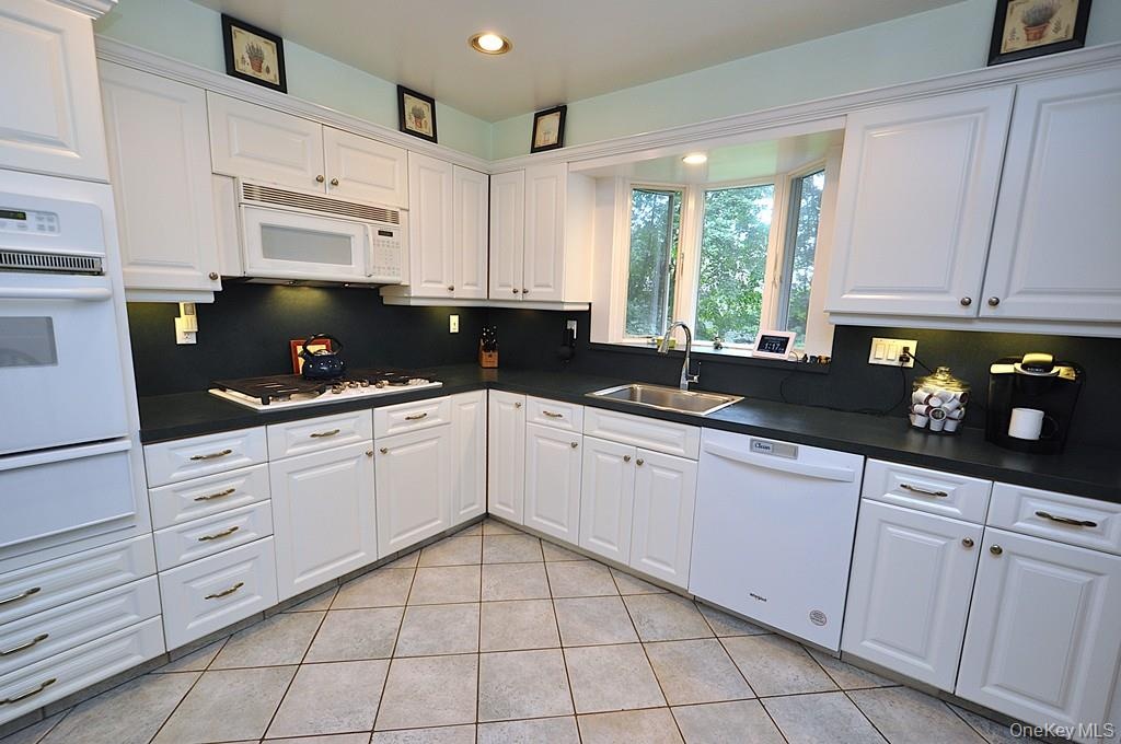 Updated Eat-in-kitchen with granite counters, Stainless Steel French Door refrigerator, wall oven, stove top, and microwave.  There is a window over t
