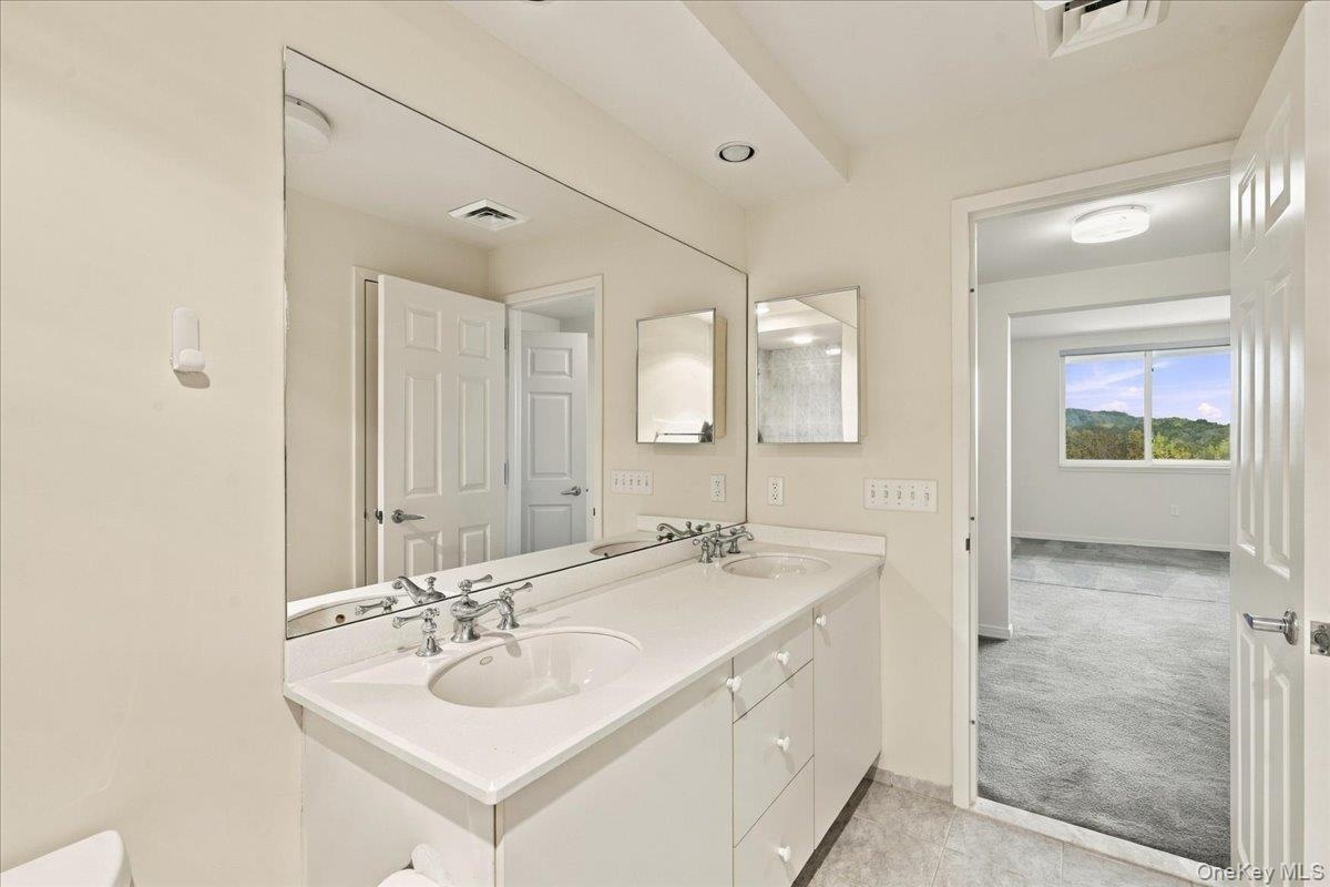 Dual vanity with integrated sinks and chrome fixtures, framed by a large wall mirror
