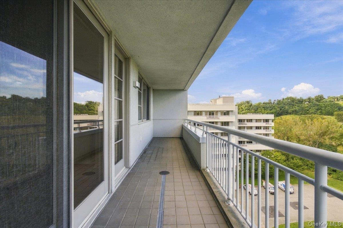 Tiled balcony with a white metal railing and a sliding glass door
