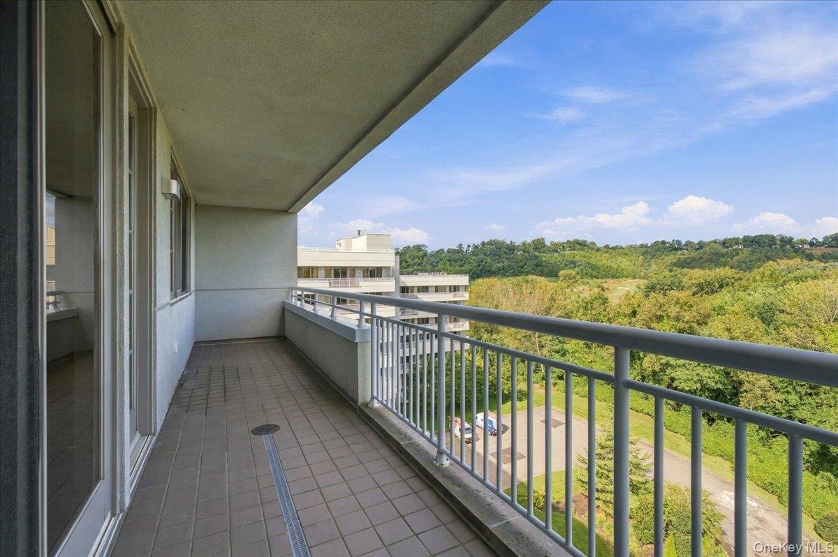 Balcony featuring tile flooring, a metal railing, and a verdant landscape backdrop