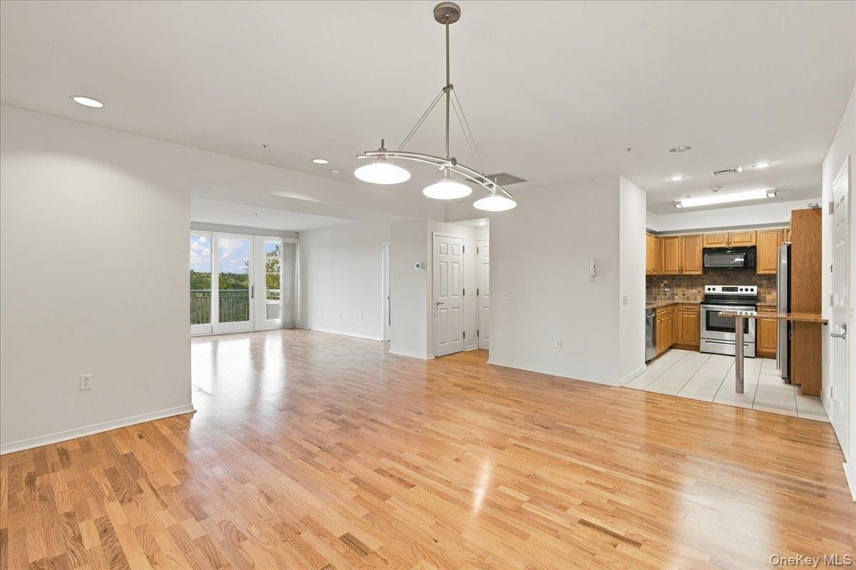 Hardwood flooring throughout the main living area, with a kitchen featuring wood cabinetry, stainless steel appliances, and a tiled floor