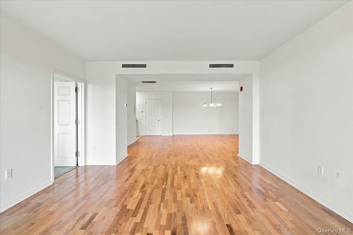 Hardwood flooring throughout, white painted walls, recessed lighting, and a contemporary pendant light fixture