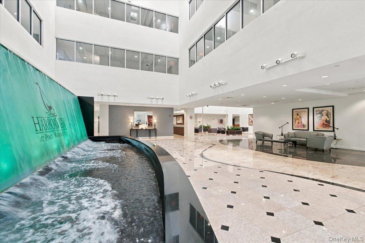 Entrance Foyer interior atrium with an illuminated water feature, polished stone flooring, and multiple seating areas