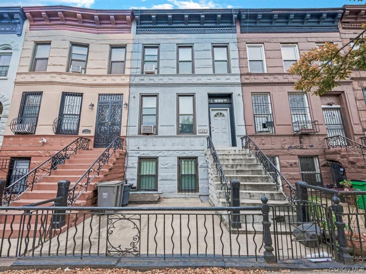 Stone facade with prominent cornice details, wrought iron fencing, and a classic stoop entrance