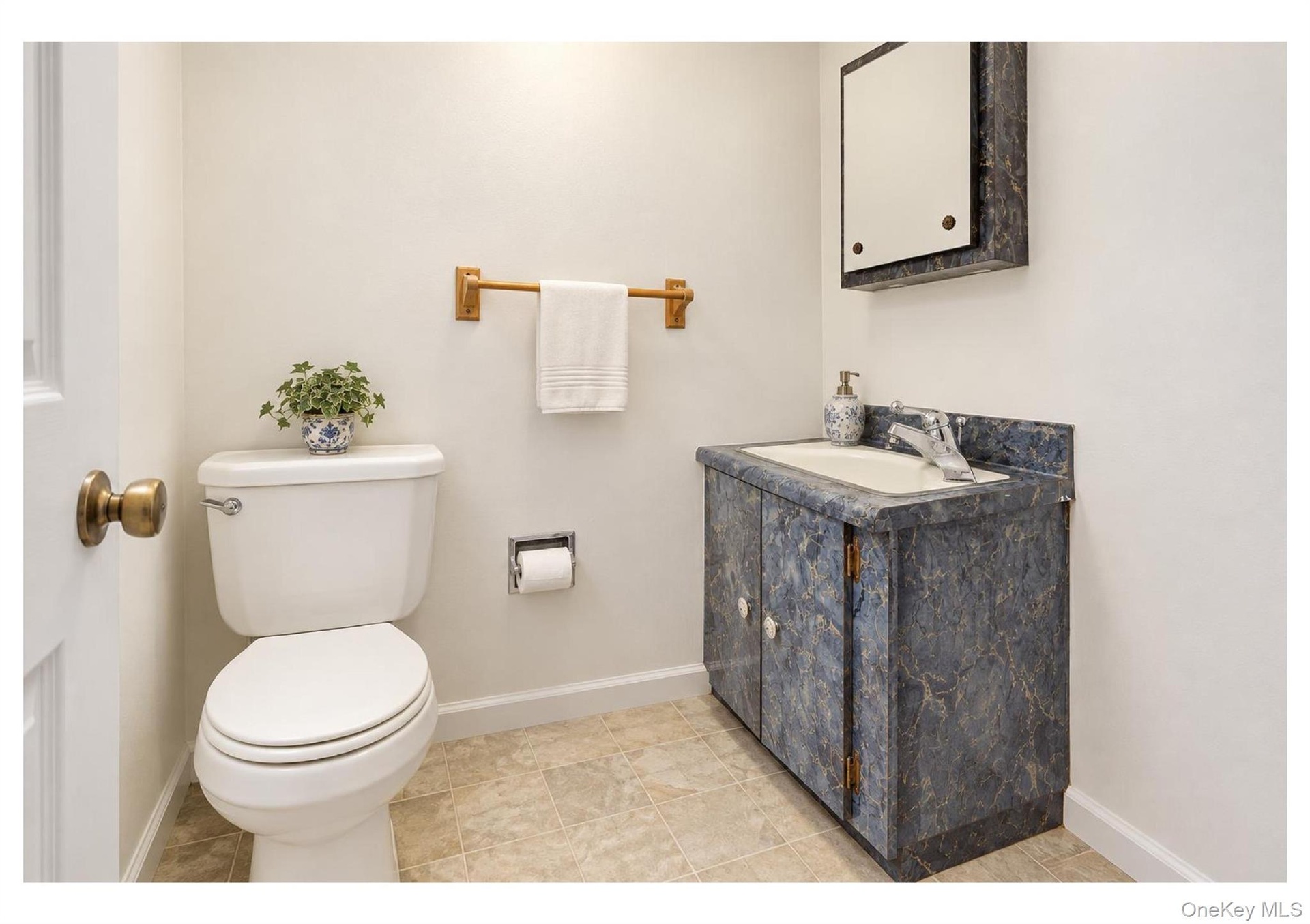 Compact bathroom featuring a vanity with an integrated sink, wall-mounted mirrored medicine cabinet, and tile flooring