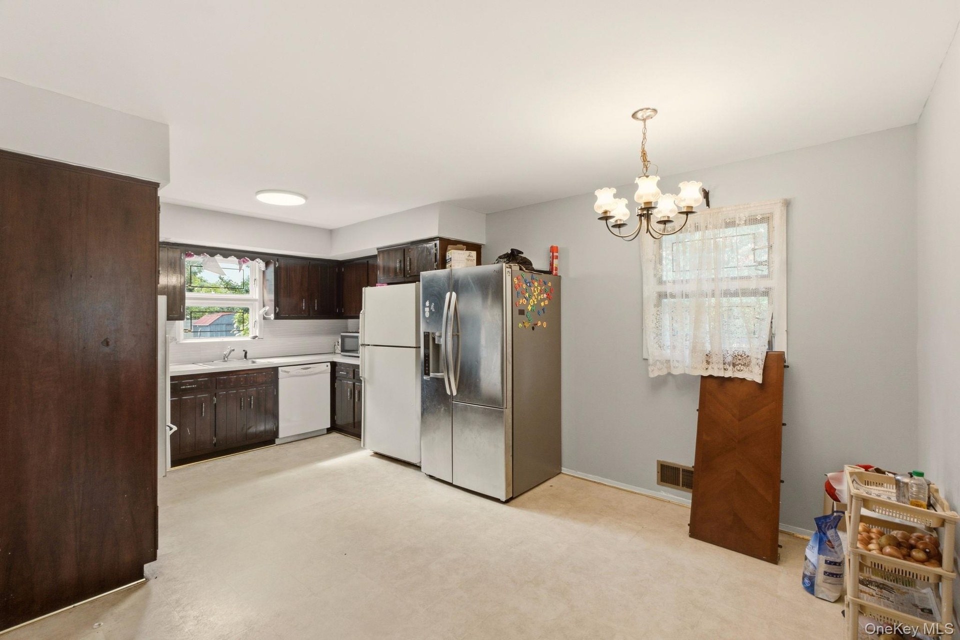 Kitchen featuring dark wood cabinetry, white appliances, and a window above the sink