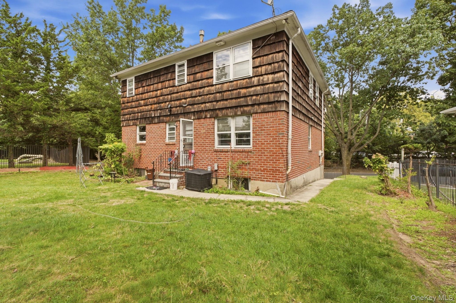 Brick and wood-shingle exterior with multiple windows and a grassy yard