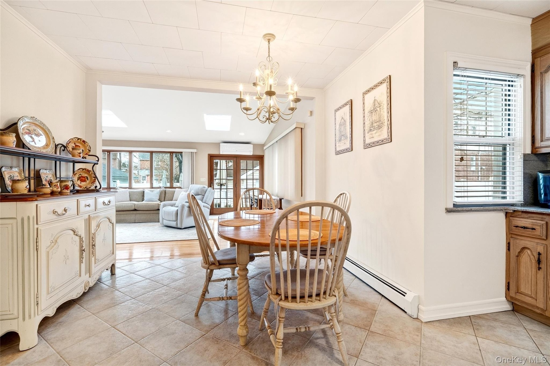 Dining area featuring a chandelier, light tile patterned floors, ornamental molding, french doors, and a skylight