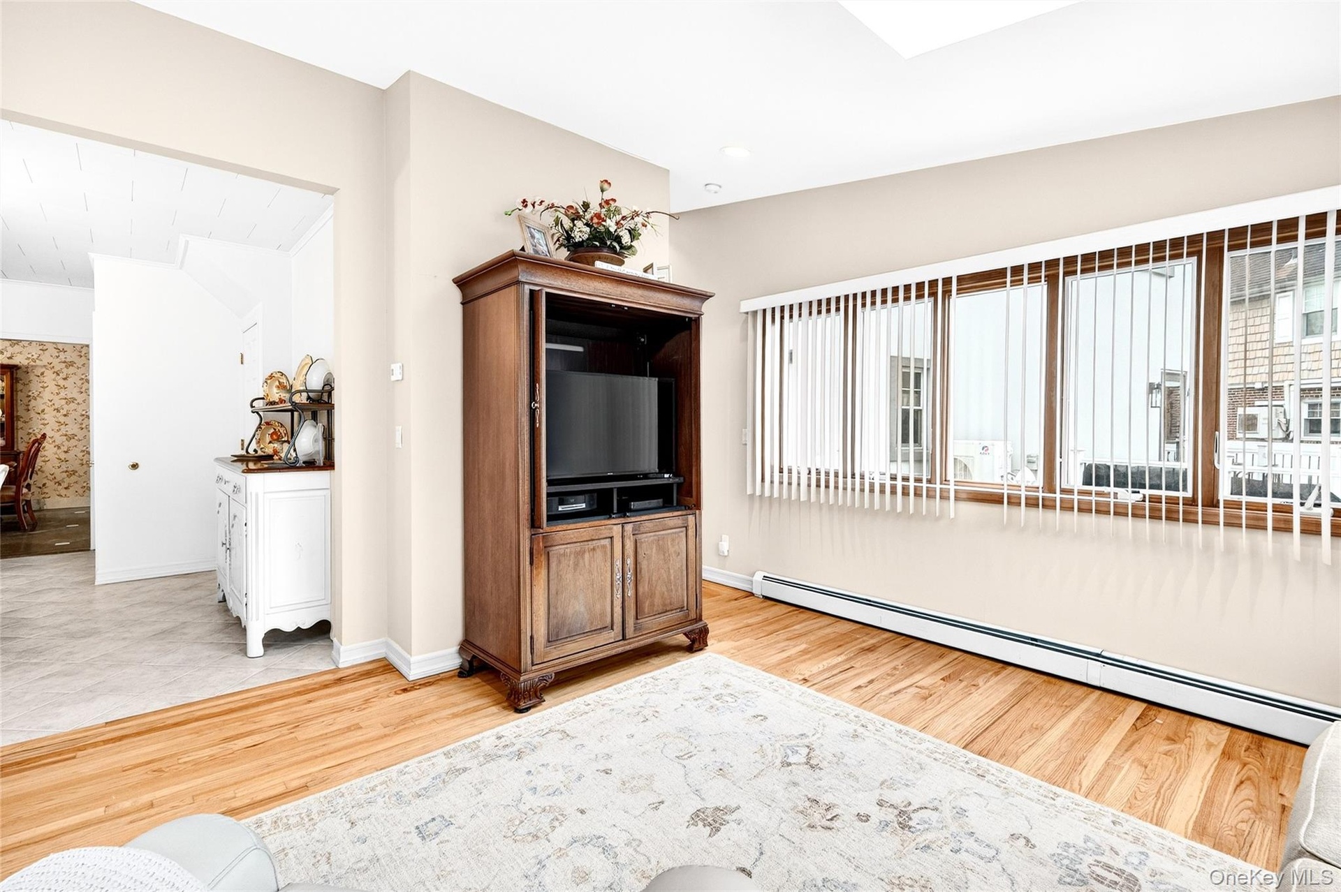 Living area with baseboard heating, healthy amount of natural light, and light wood-type flooring