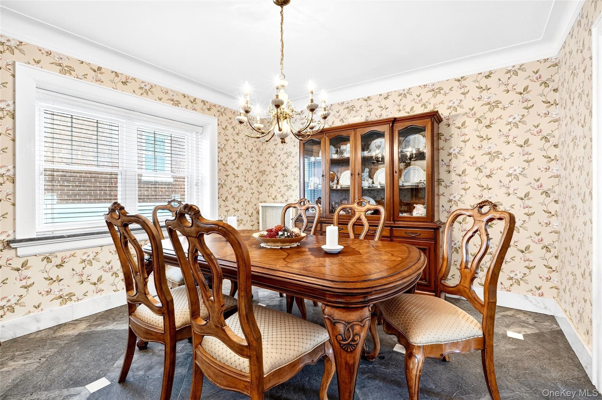 Dining space featuring wallpapered walls, a chandelier, and crown molding