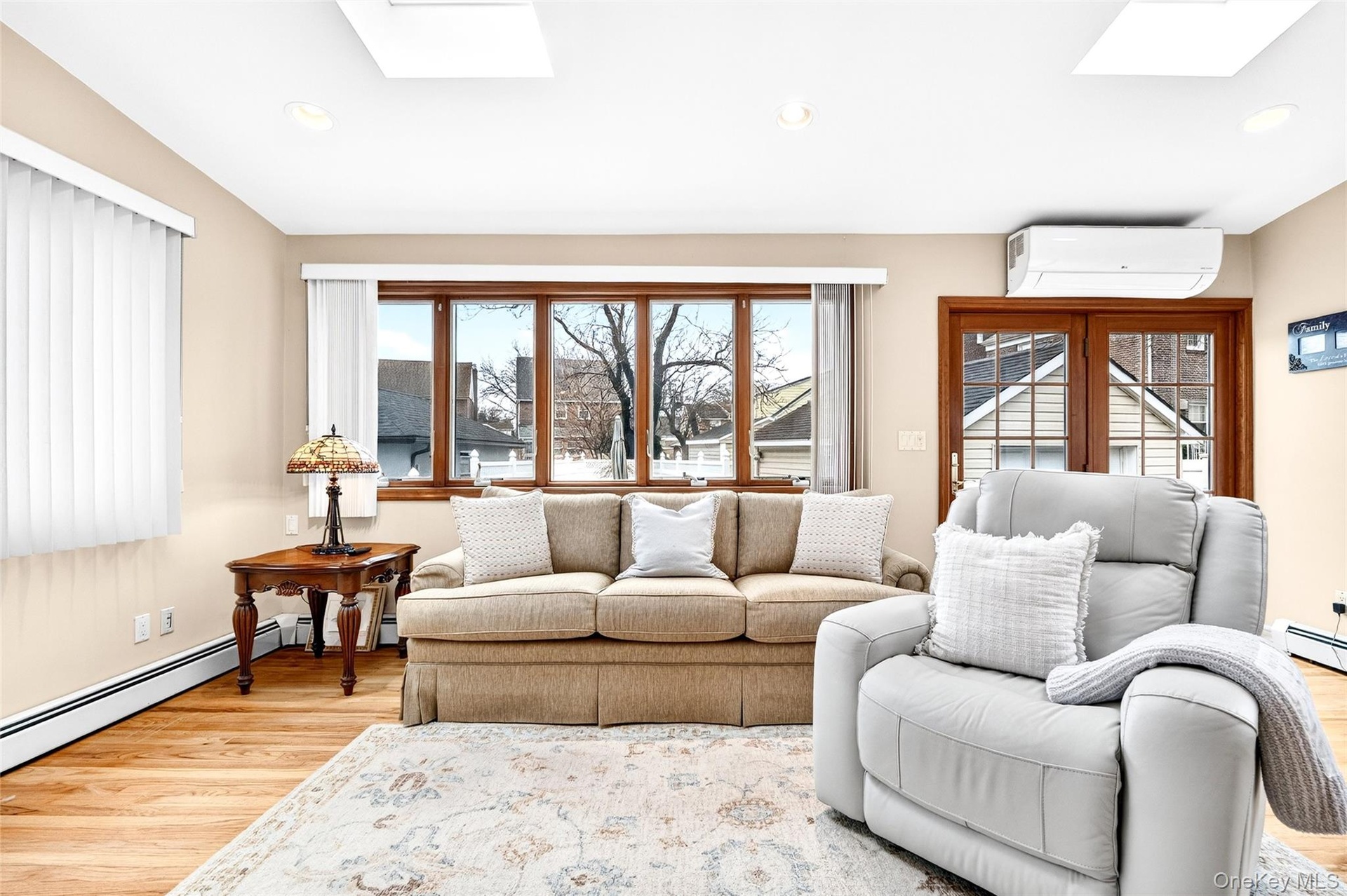 Living room featuring a skylight, light wood-style floors, a wall mounted AC, and recessed lighting