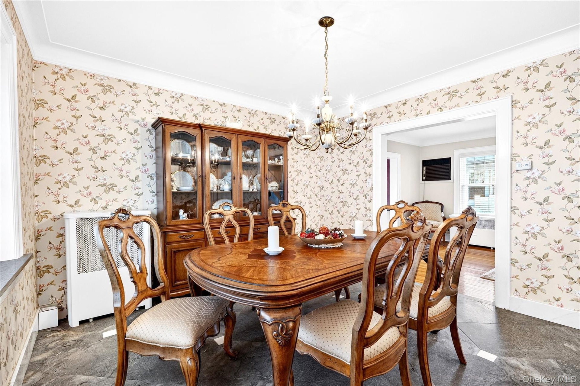 Dining room with a chandelier, radiator heating unit, wallpapered walls, and ornamental molding
