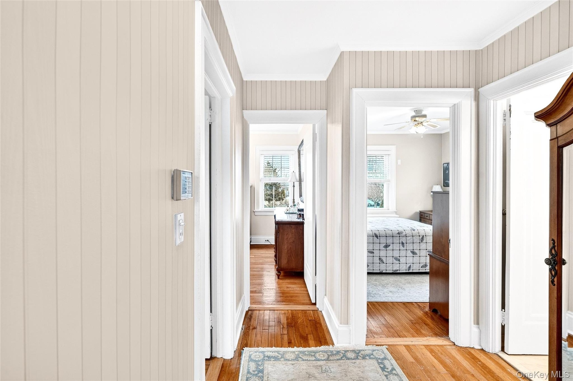 Hallway with light wood-type flooring and ornamental molding