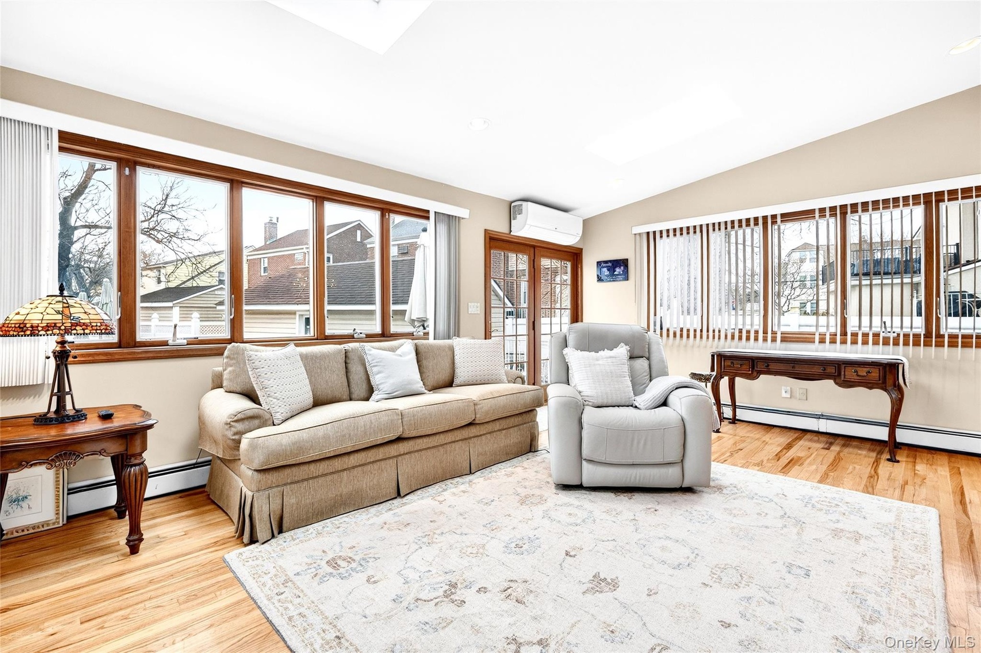 Living room featuring lofted ceiling, light wood-style floors, healthy amount of natural light, and a wall mounted AC