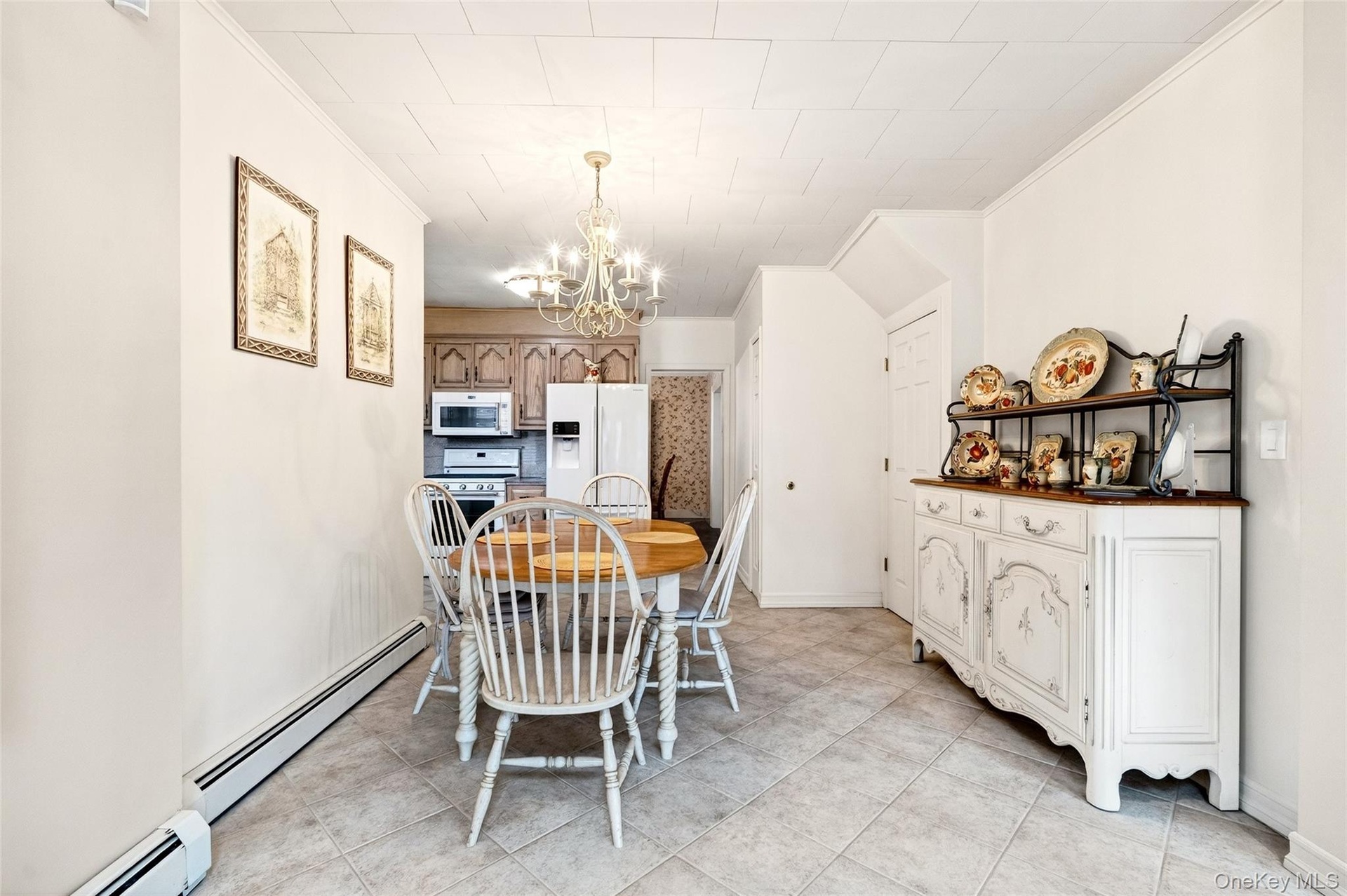 Dining room featuring a baseboard radiator, ornamental molding, a chandelier, and light tile patterned floors
