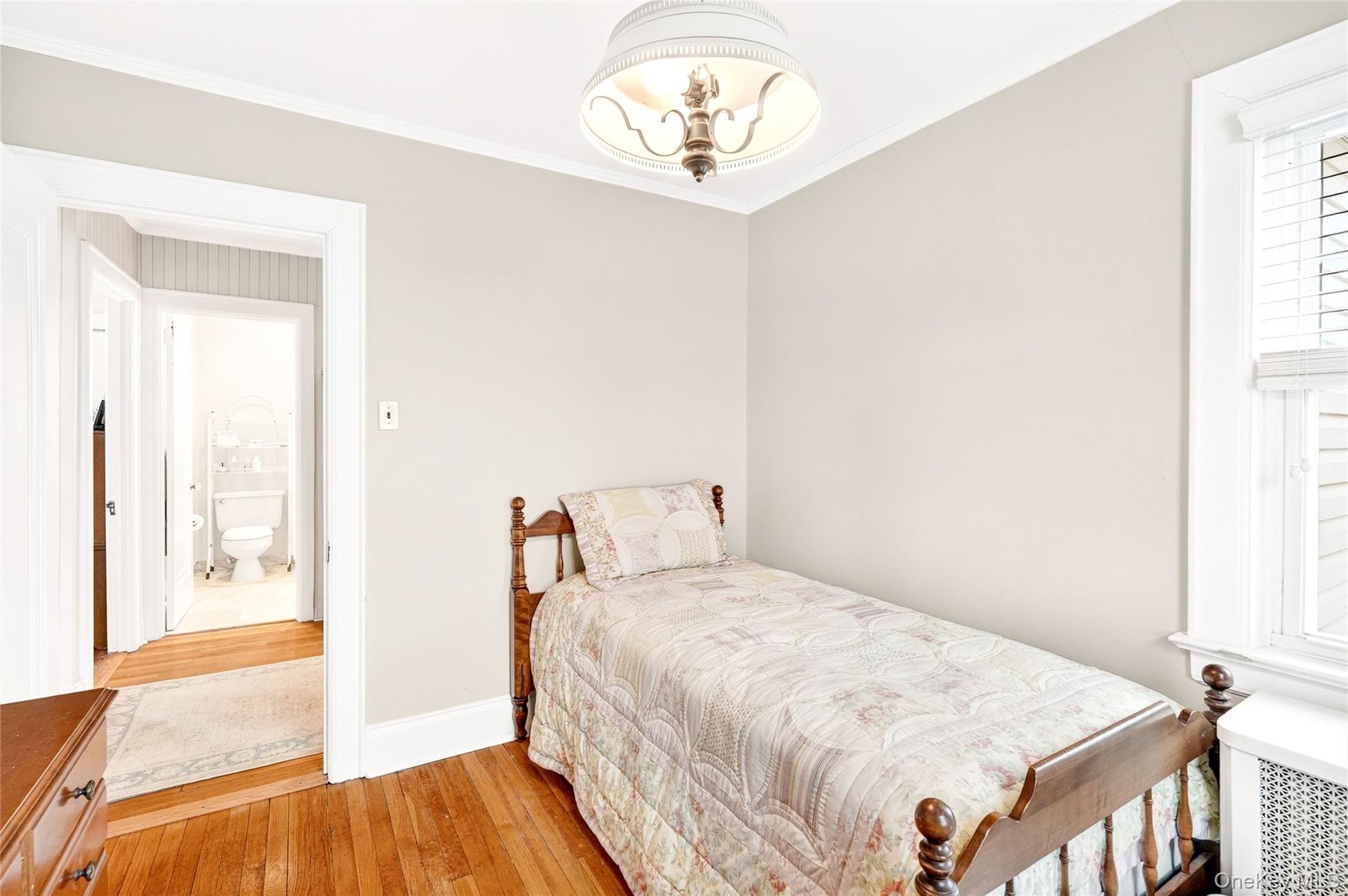 Bedroom with radiator, light wood-type flooring, and crown molding