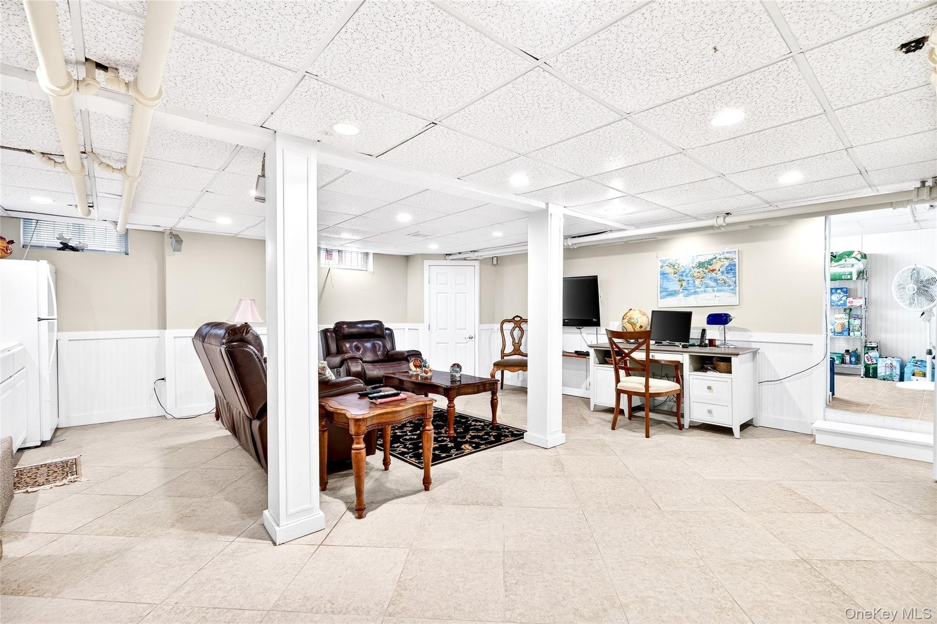 Office area featuring a wainscoted wall, a paneled ceiling, and light tile patterned floors