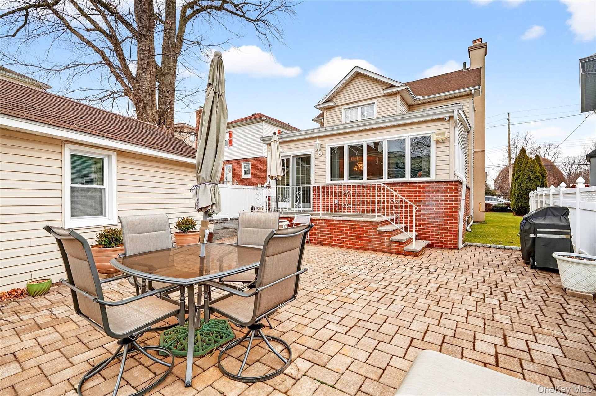 Back of property featuring outdoor dining space, a patio, a chimney, brick siding, and roof with shingles