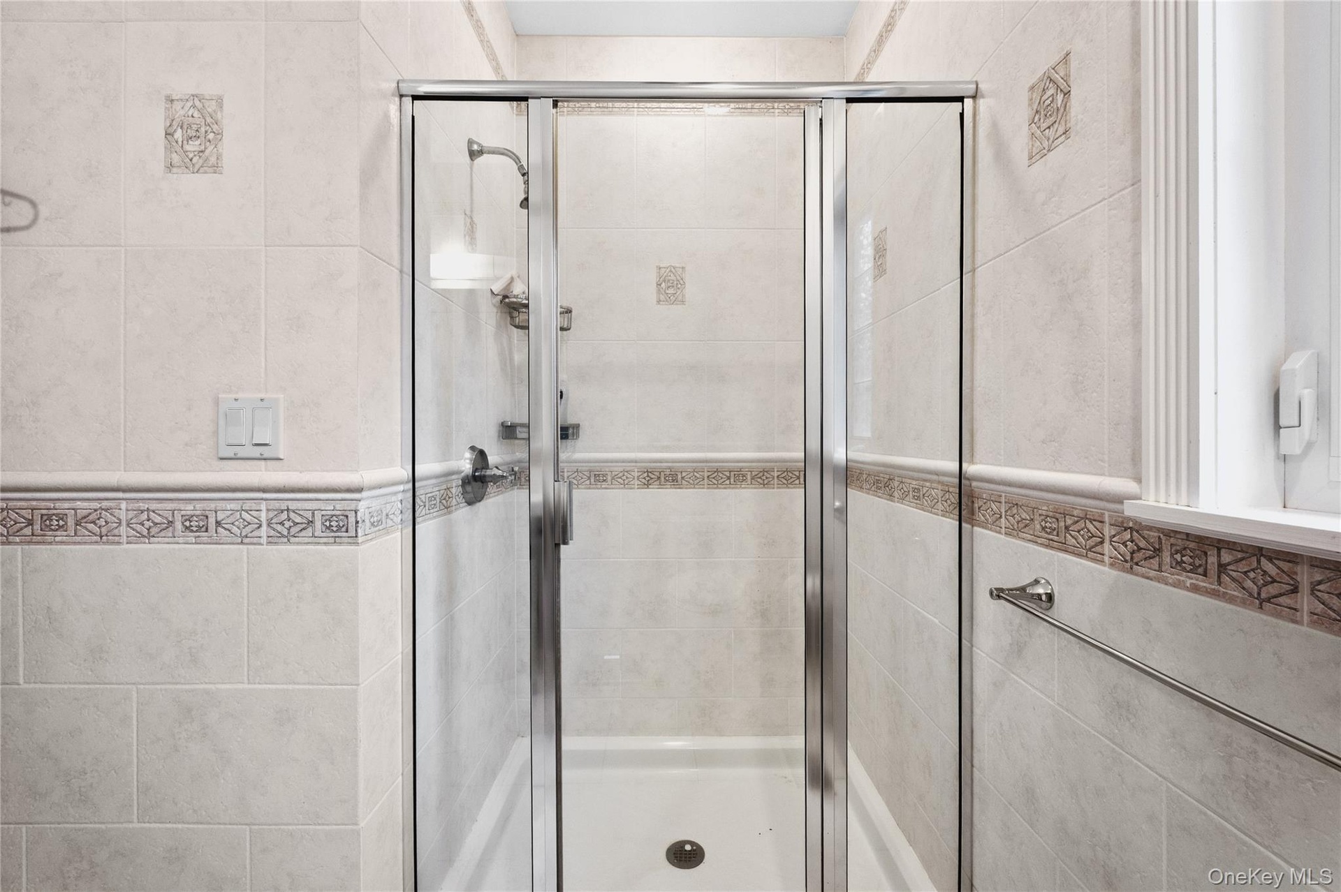 Glass-enclosed shower with a handheld showerhead