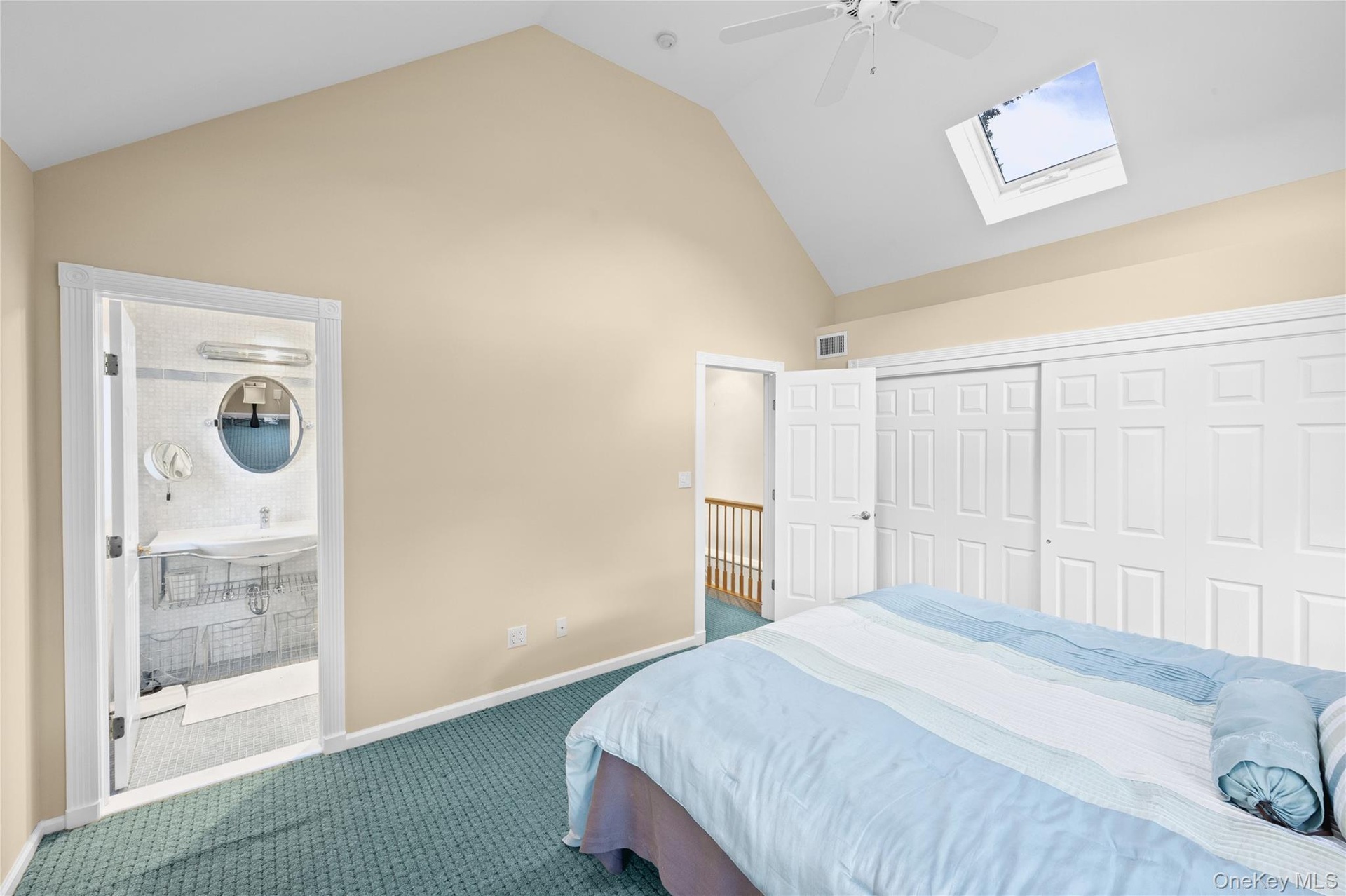Vaulted ceiling with skylight and ceiling fan, neutral wall tones, and sliding closet doors