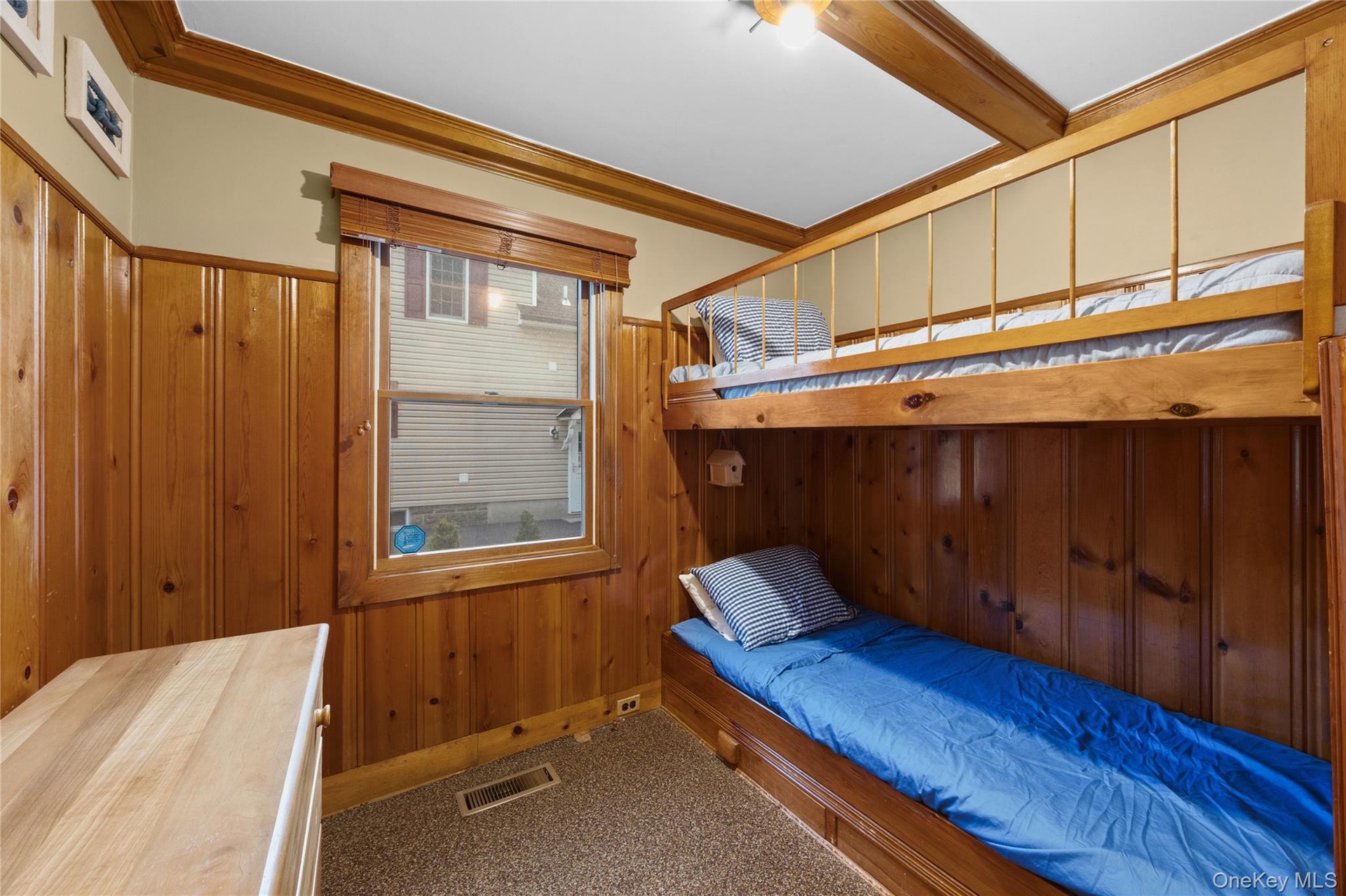 Wood paneling walls, wood-finish bunk bed, wood-frame window, exposed wood beams, and carpeted flooring