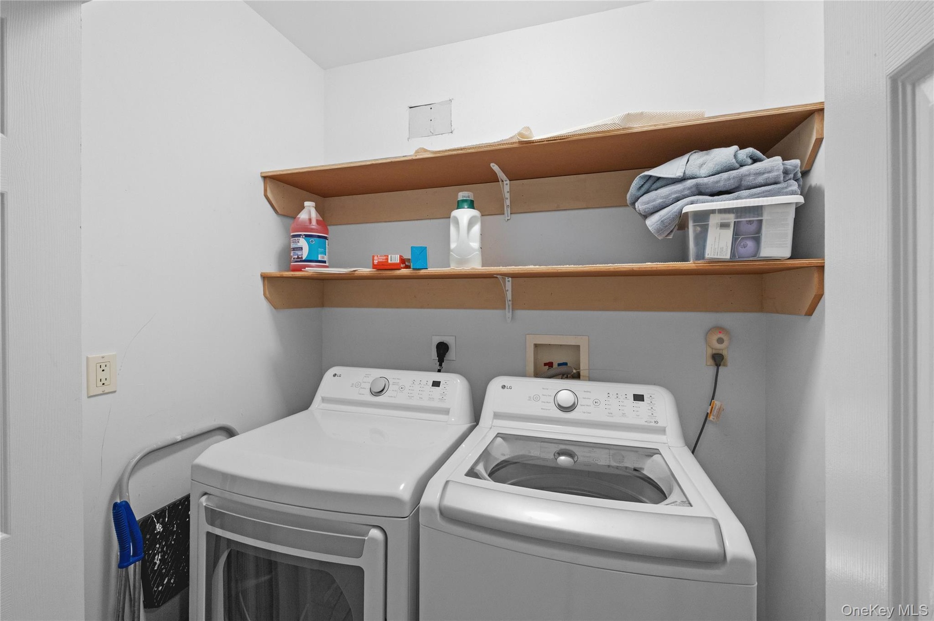 Laundry area featuring dual built-in shelves and white walls