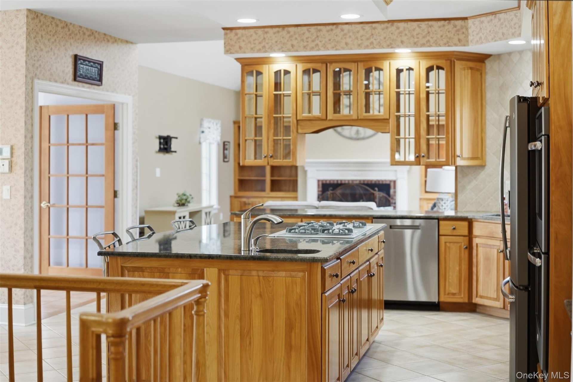 The kitchen features a central island with a sink and stovetop, wood cabinetry, and stainless steel appliances