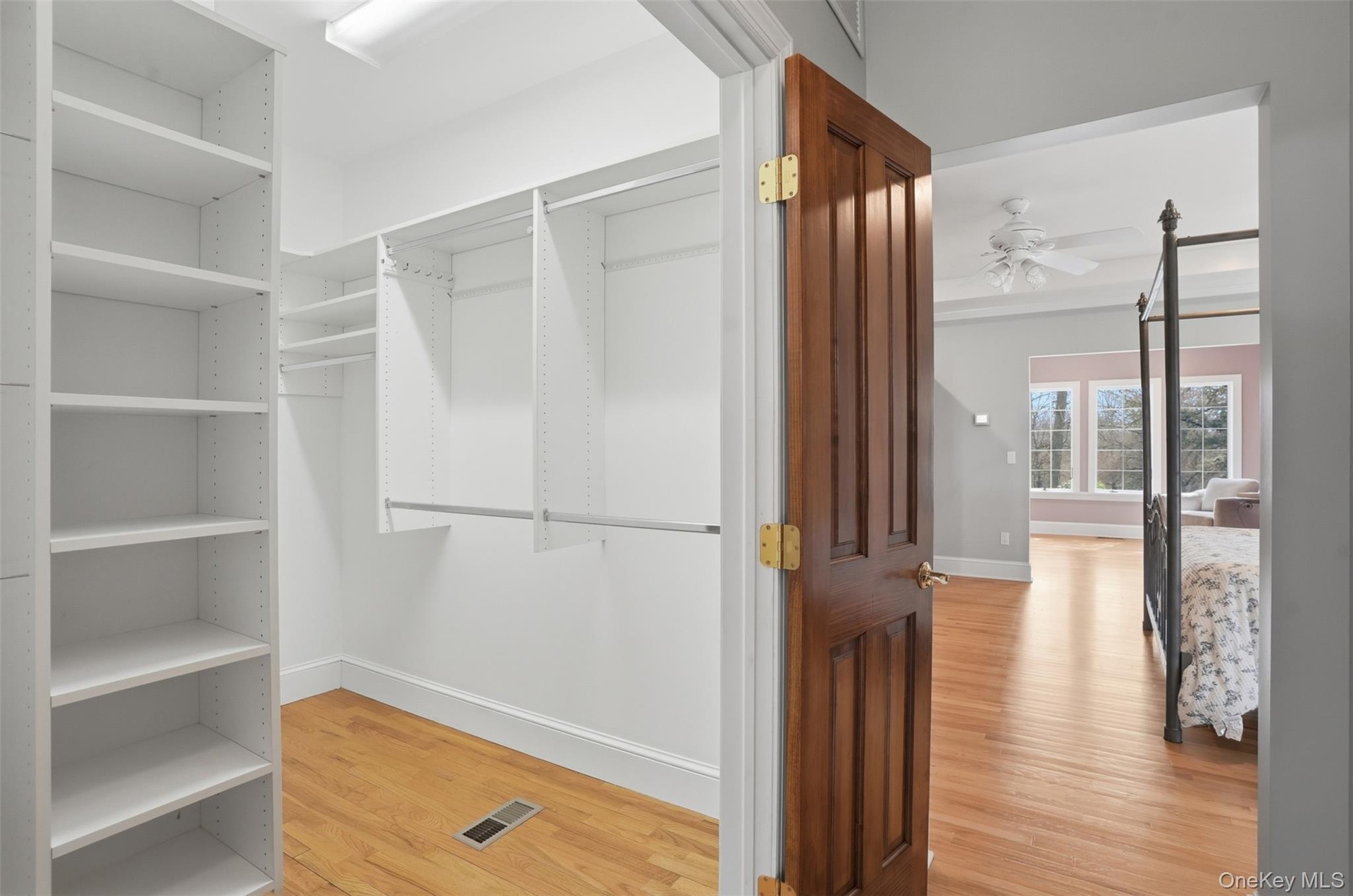 Walk-in closet featuring extensive built-in shelving and hanging rods