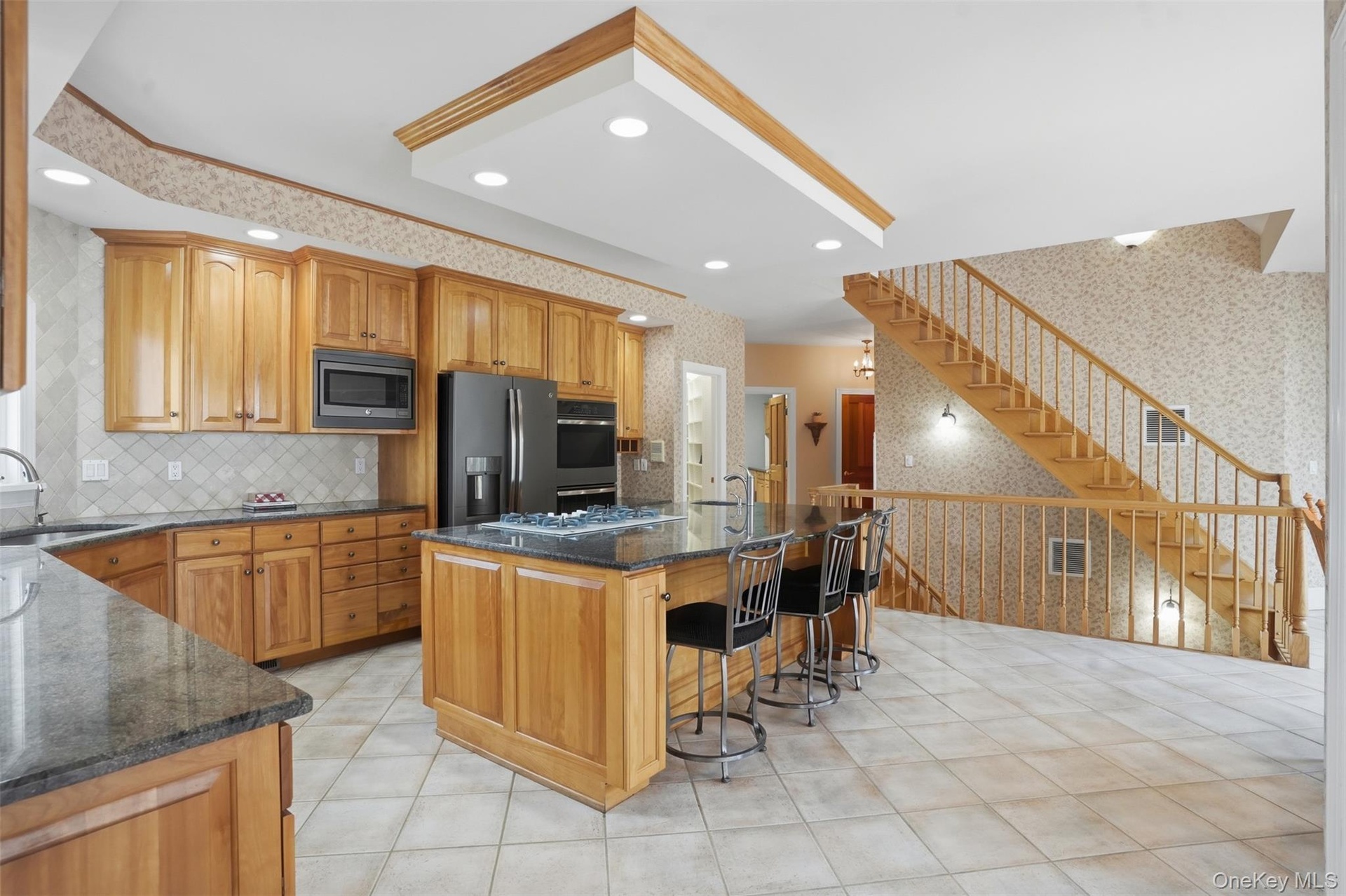 The kitchen features wood cabinetry, dark countertops, and modern appliances