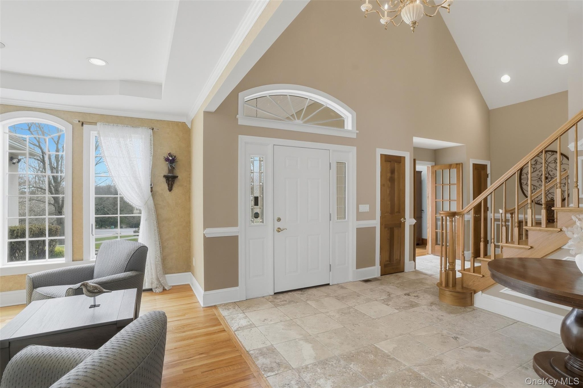 The property features a grand entryway with high ceilings, an elegant staircase with wood banisters, and arched windows
