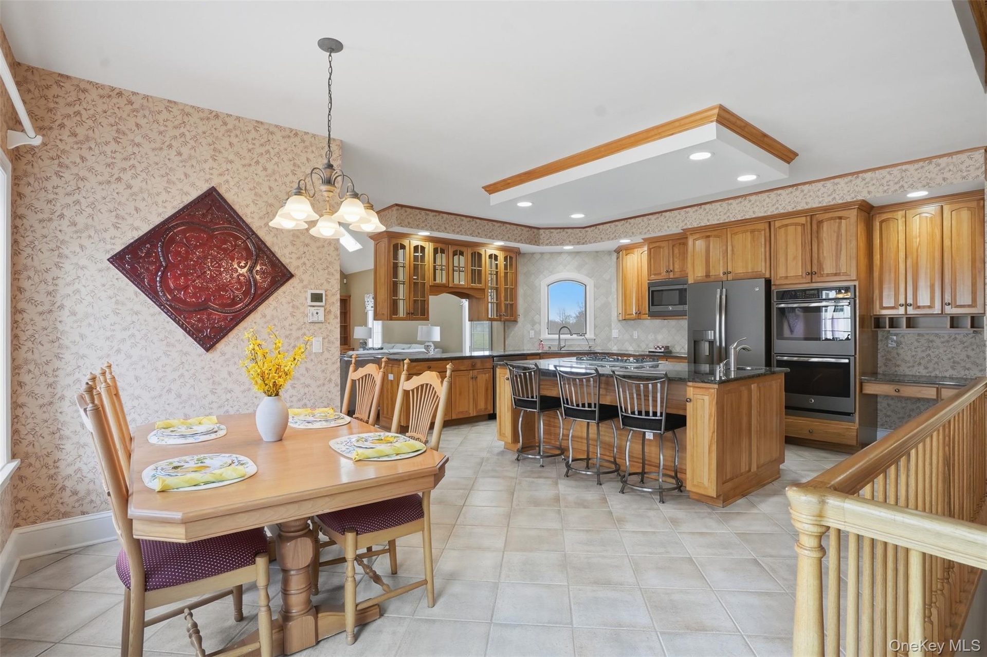 This property features a kitchen and dining area with hardwood cabinetry, a kitchen island with seating, a large refrigerator, and a double oven
