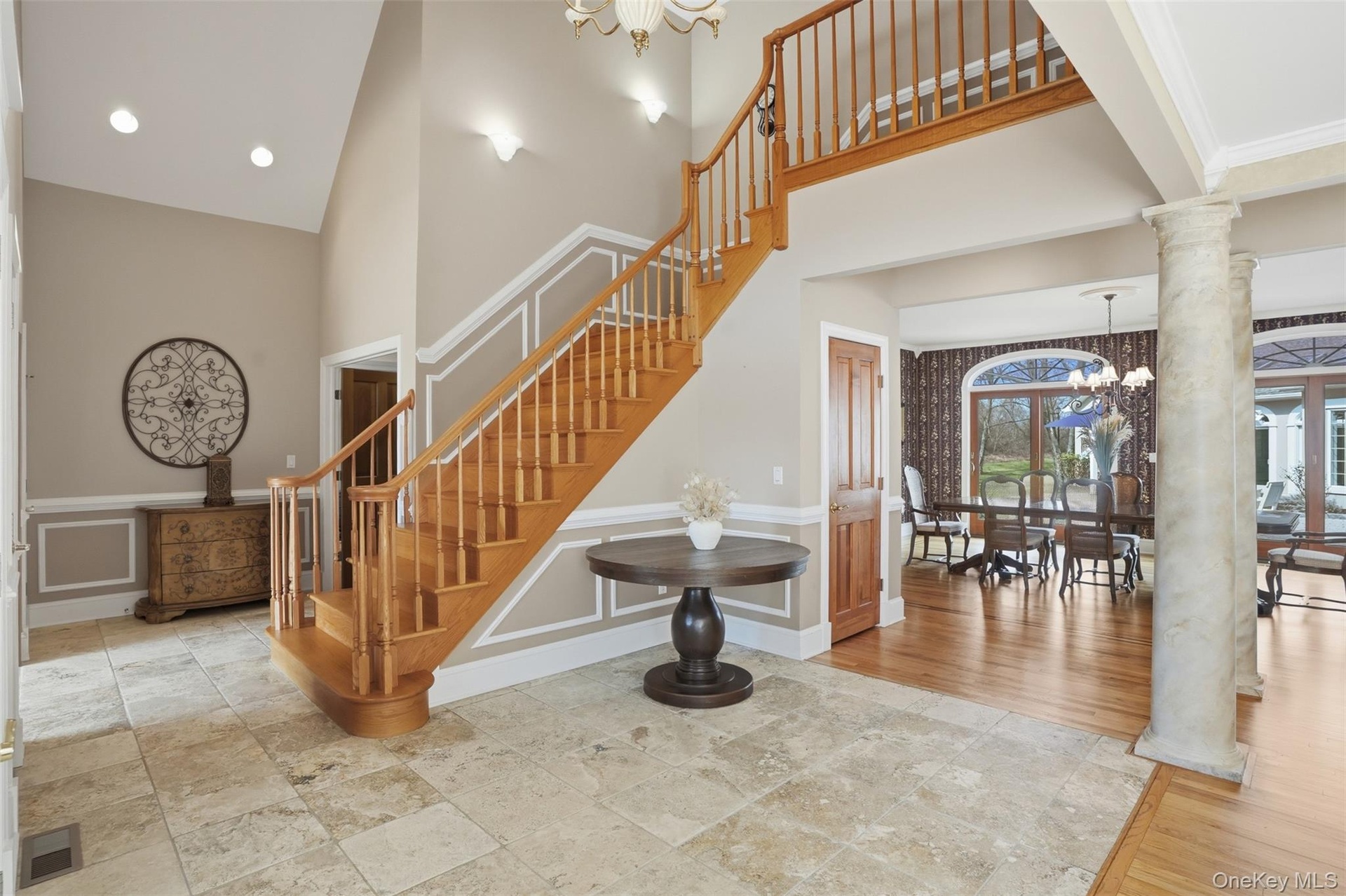 Grand foyer featuring a natural wood staircase with white risers, a vaulted ceiling, and recessed lighting