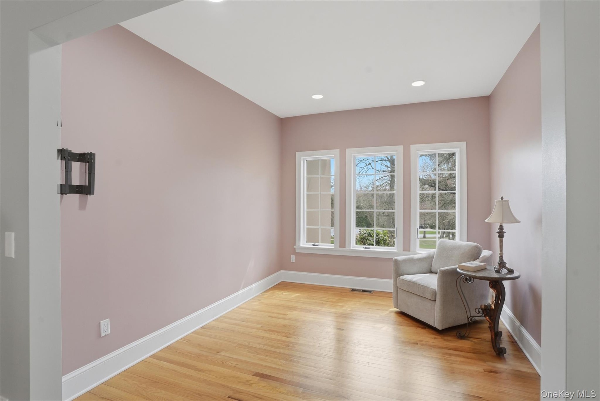 This room features hardwood floors, three windows providing natural light, and recessed ceiling lighting