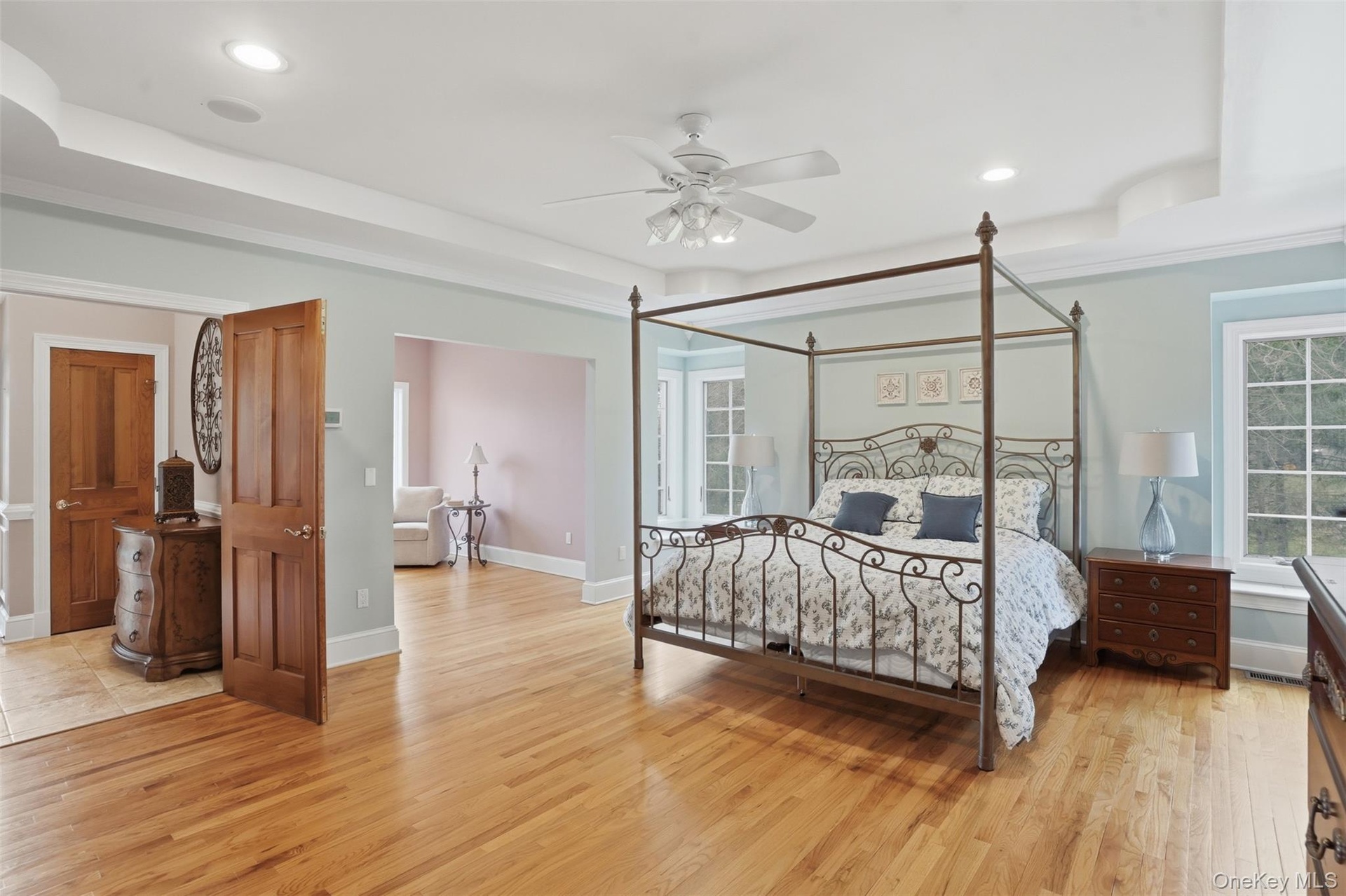 This spacious room features hardwood floors, a ceiling fan, recessed lighting, and windows providing natural light