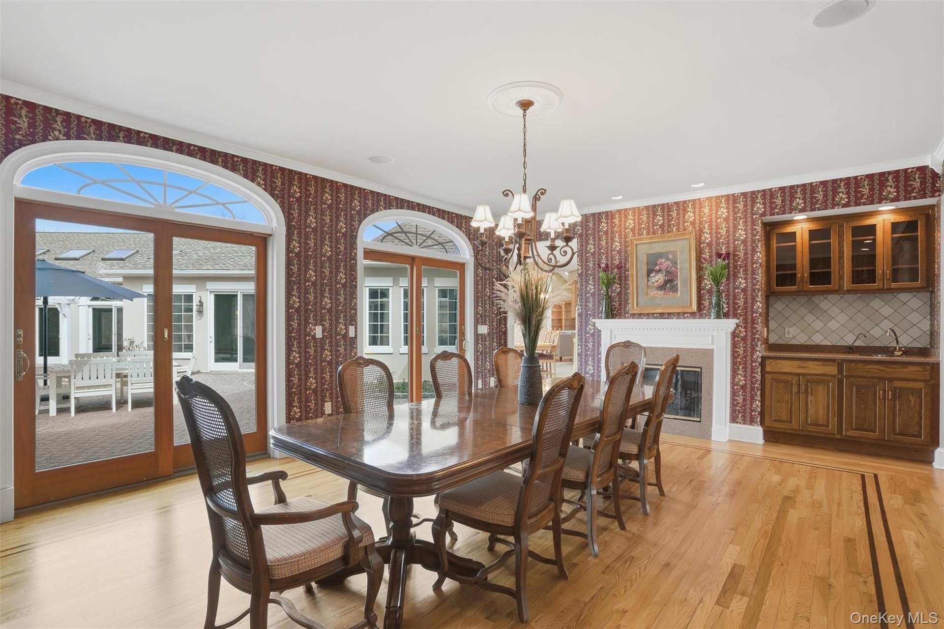 This dining area features hardwood floors, a decorative fireplace, and a built-in wet bar with wood cabinetry and a tiled backsplash