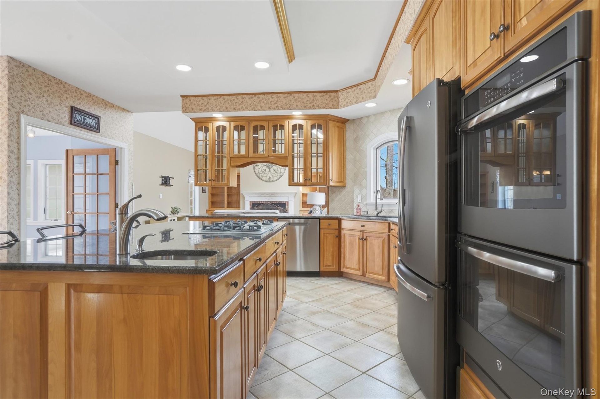 The kitchen features solid wood cabinetry, a large kitchen island with a sink, a gas stovetop, and stainless steel appliances
