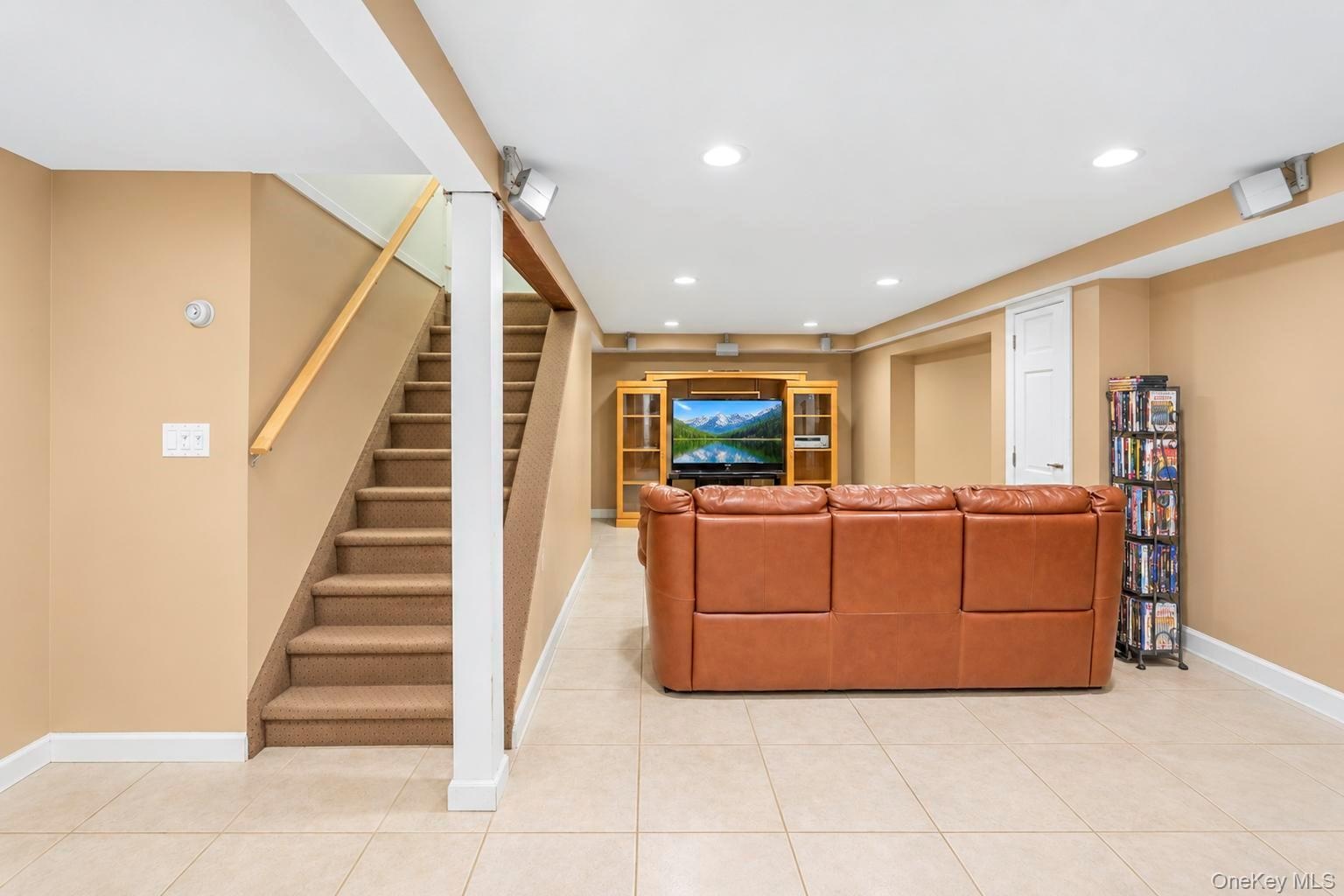 Recessed lighting illuminates this expansive space featuring tile flooring and a built-in media center