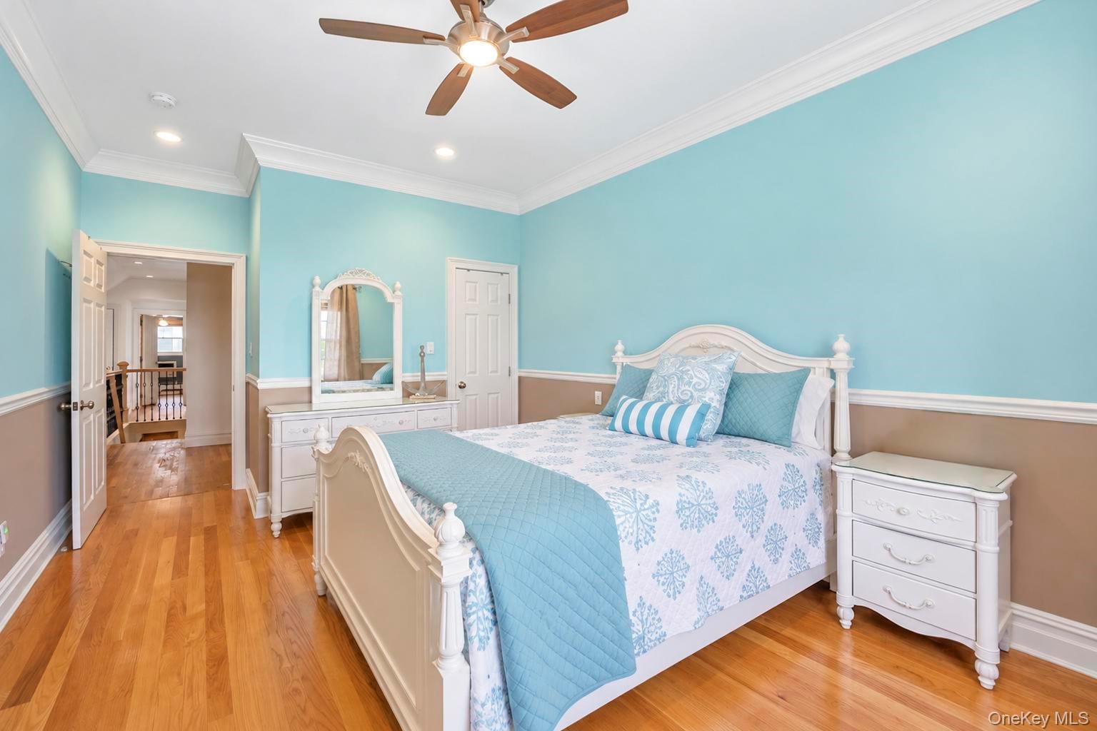 Hardwood flooring, crown molding, two-tone wall treatment, recessed lighting, and a ceiling fan with light