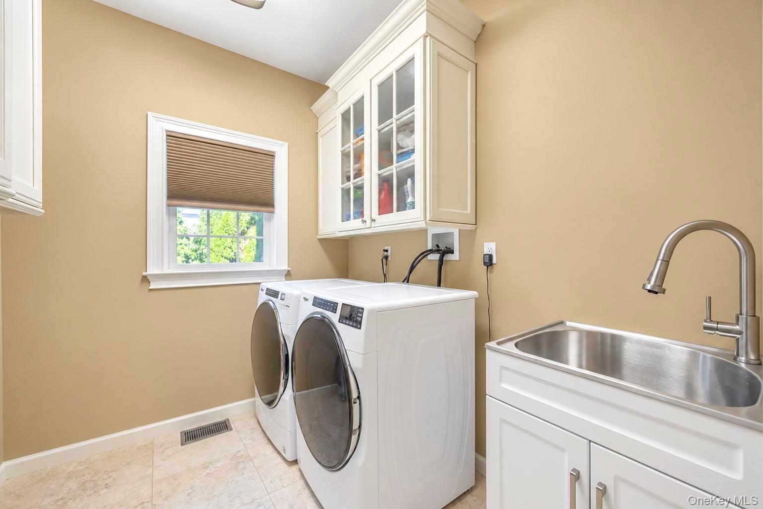 Laundry area featuring a utility sink with a pull-down faucet, white cabinetry with glass inserts, and tiled flooring