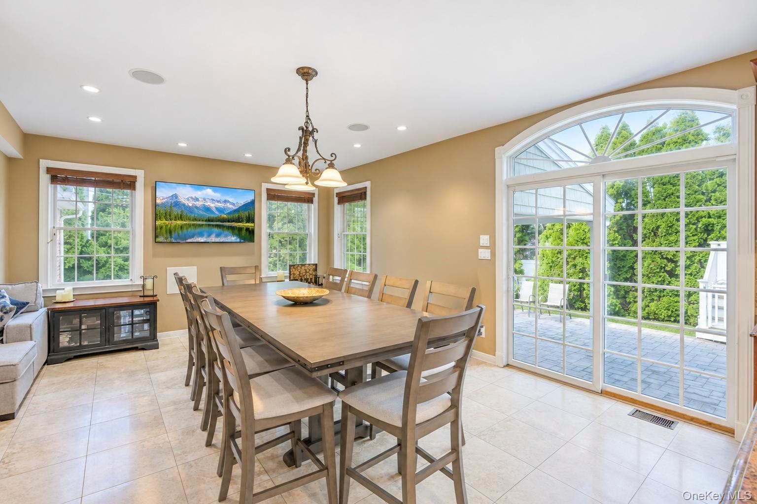 large dining table off kitchen ,Tiled flooring, recessed lighting, and a chandelier illuminate this space featuring multiple windows