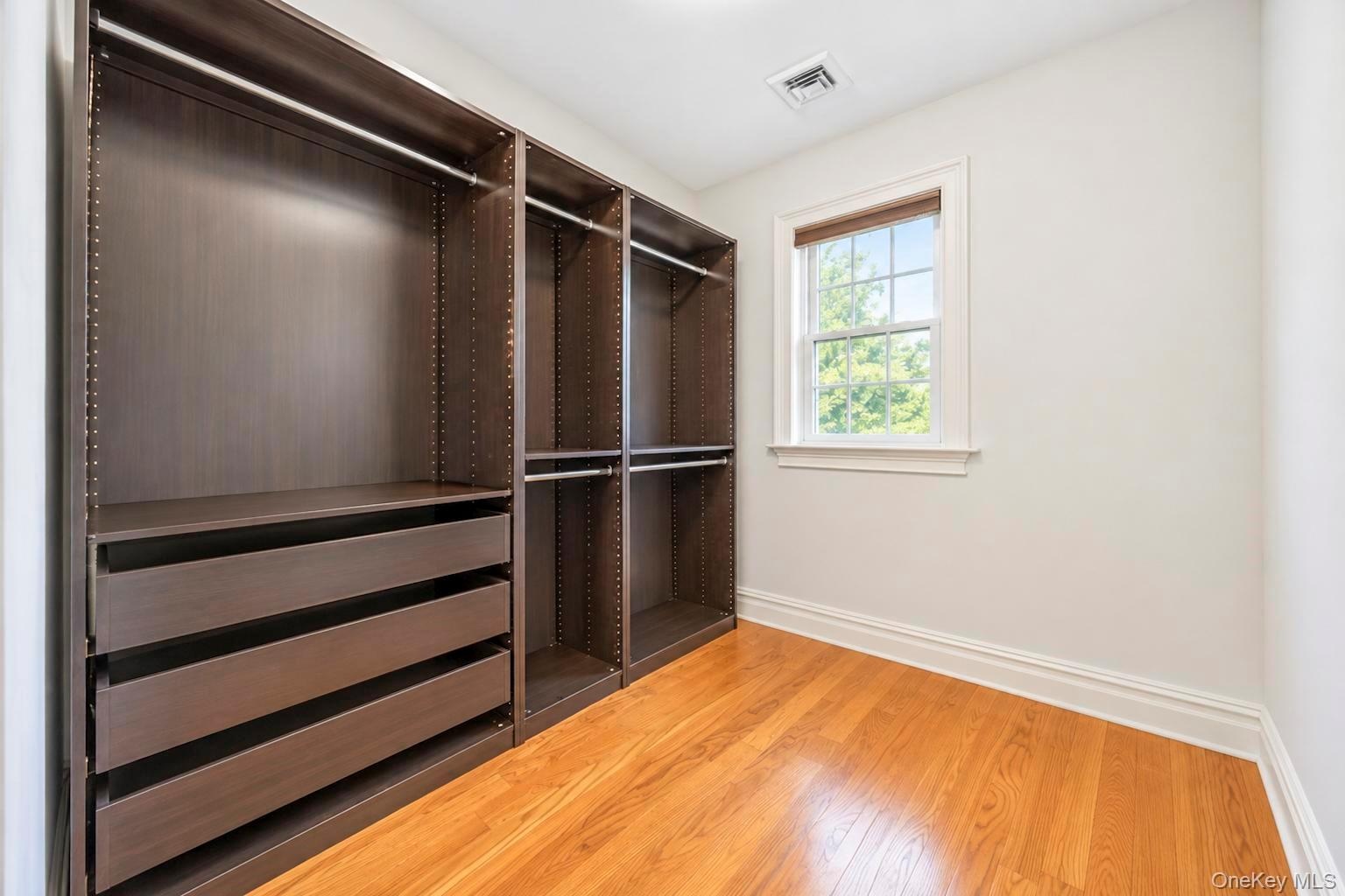 Hardwood flooring, custom built-in closet system with drawers and shelving, double-hung window, crown molding