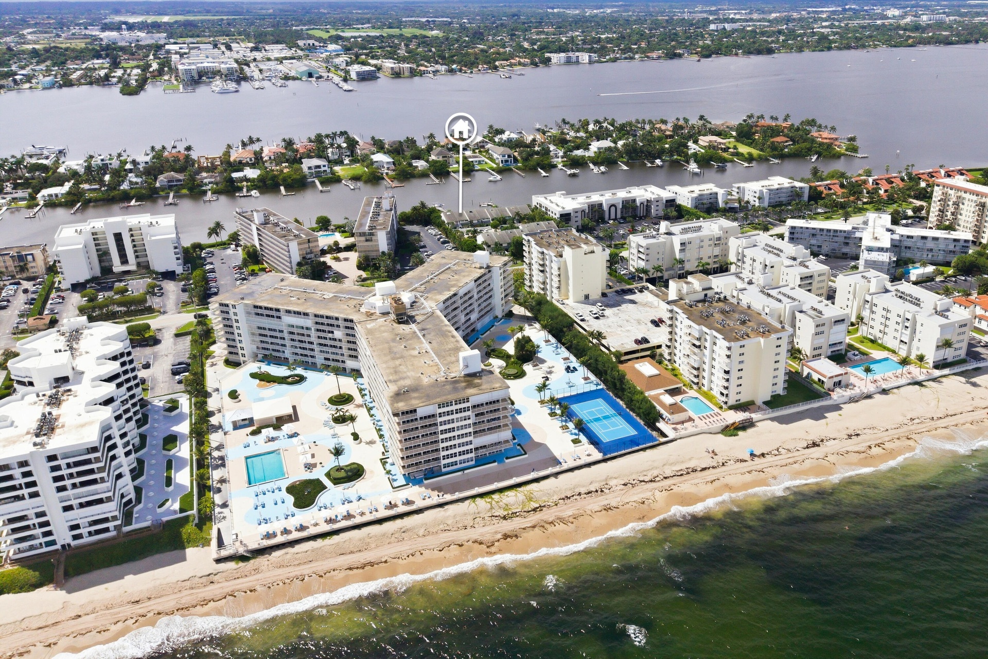 Coastal property featuring multiple buildings, direct beachfront access, multiple swimming pools, and a tennis court