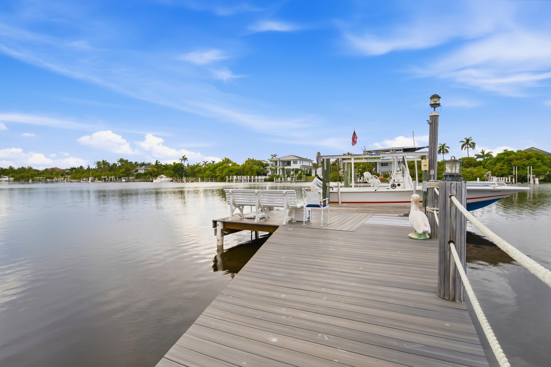 Waterfront property featuring a wood-composite dock, built-in bench seating, and boat lift