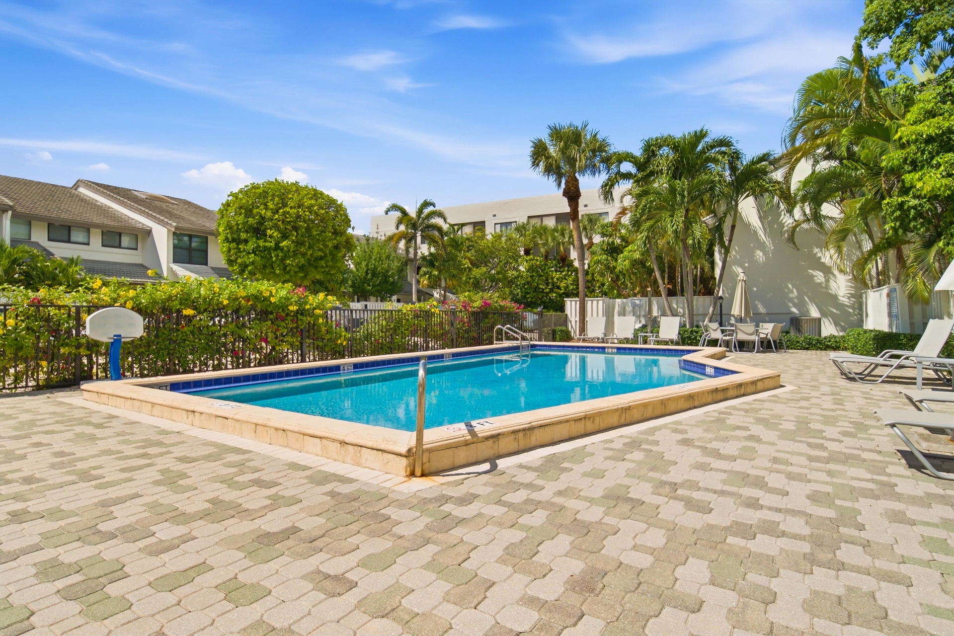Resort-style rectangular pool with blue tile accents, surrounded by a paver deck