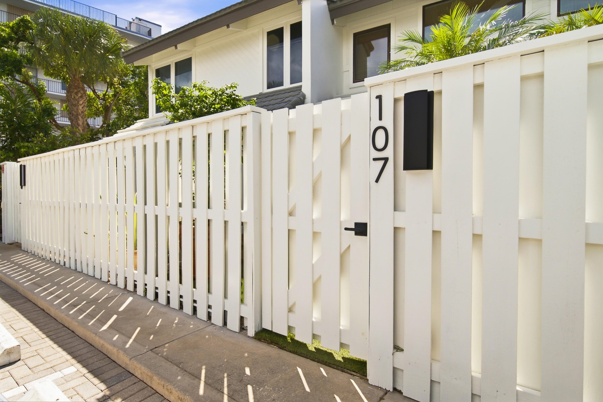 White picket fence with a modern gate and black house numbers