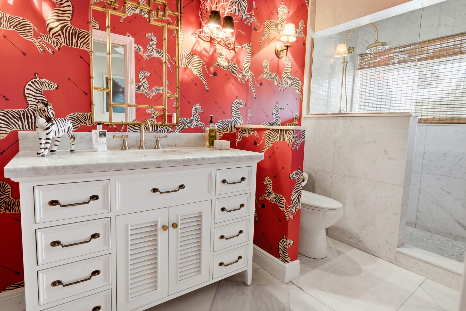 White vanity with a stone countertop, dual undermount sinks, and a decorative gold-toned mirror