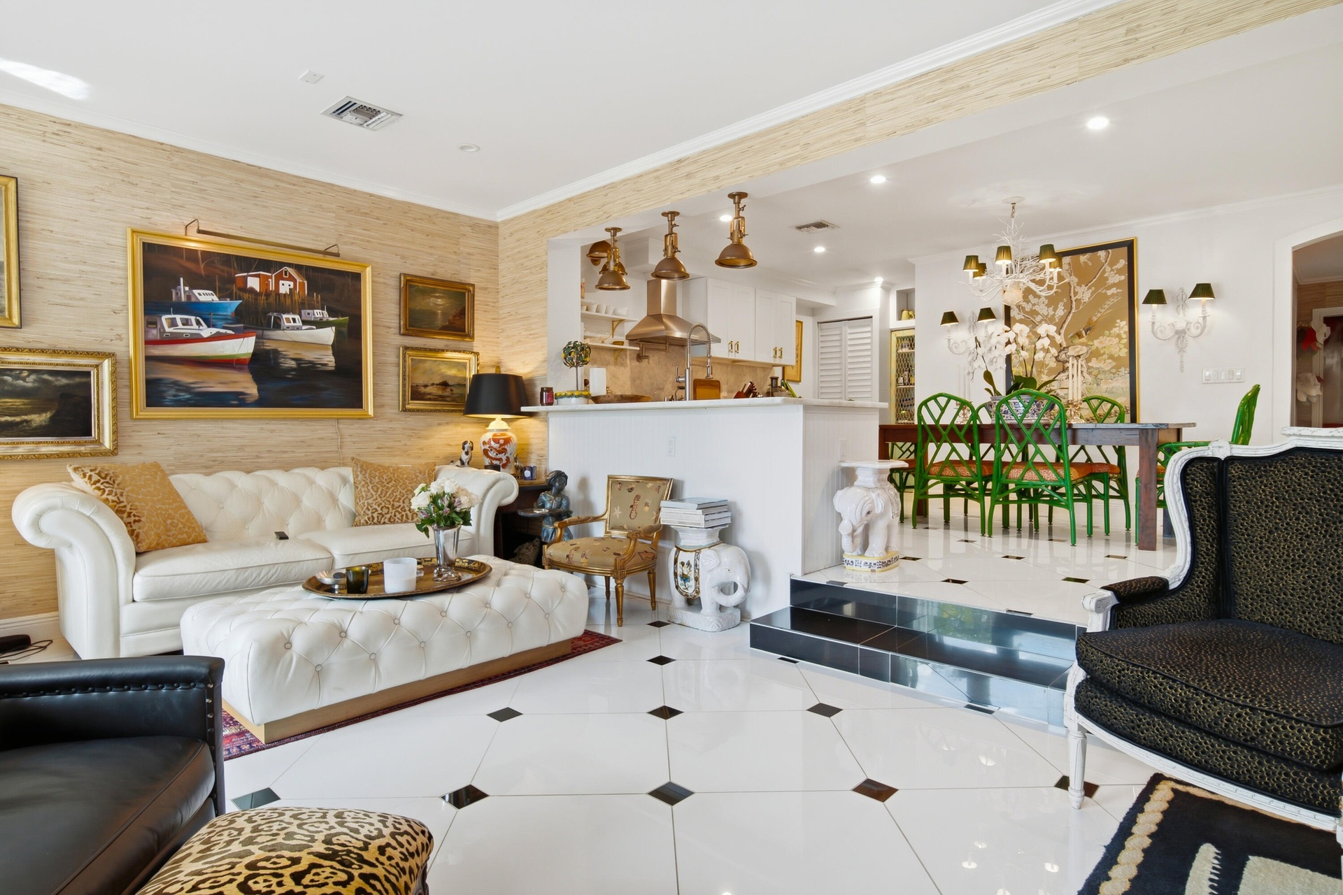 Open-concept living area with large-format floor tiling and wall sconces, featuring a kitchen peninsula with pendant lighting and a dining area