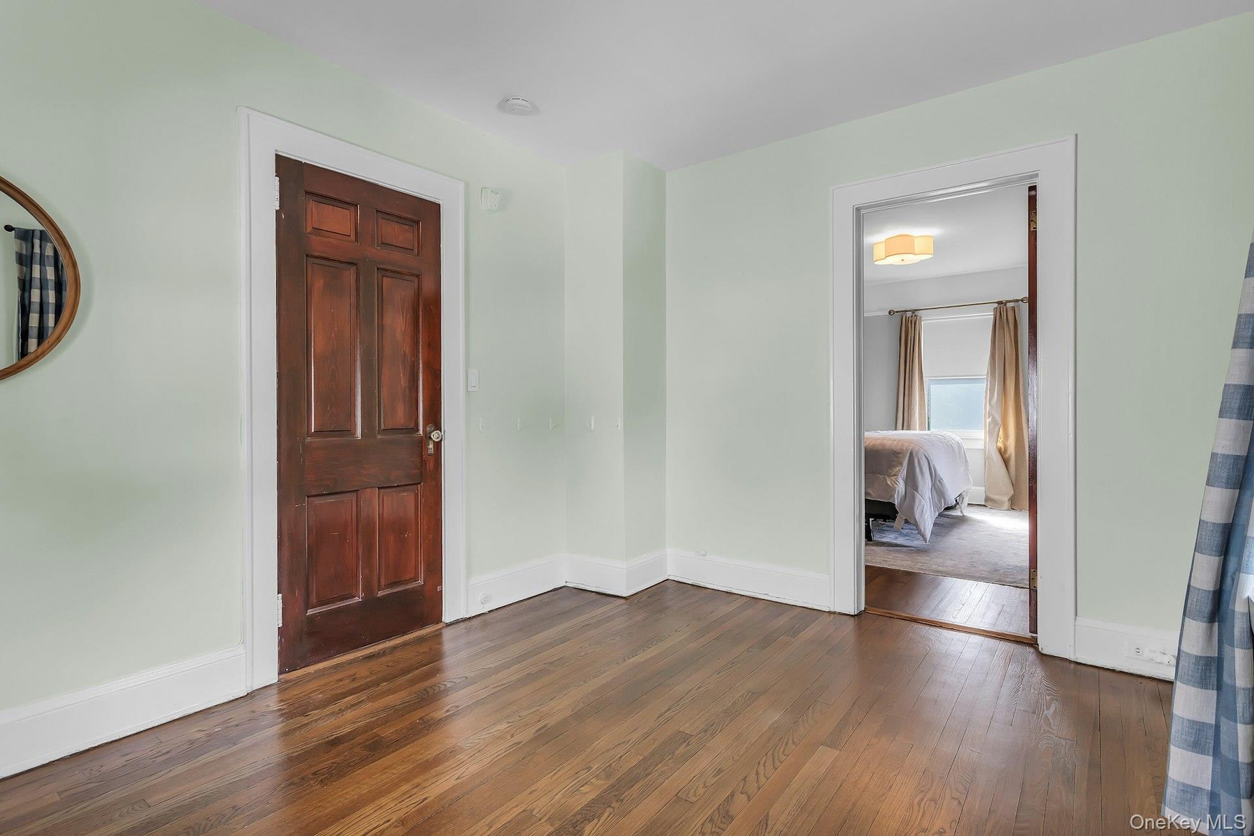 Hardwood flooring, painted walls, solid panel interior door, and a cased opening
