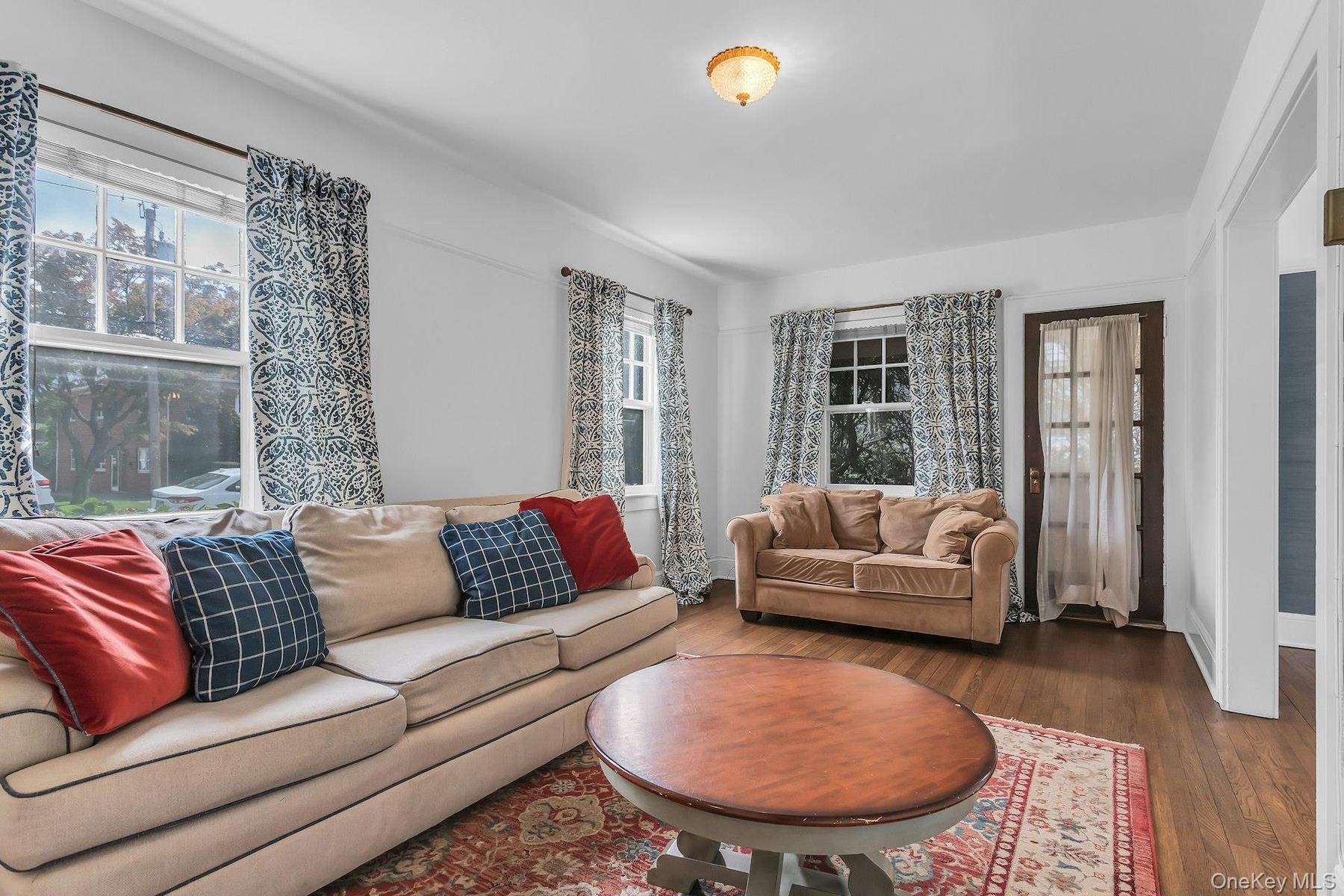 Hardwood flooring, multiple windows providing natural light, white wall finishes, and a classic ceiling fixture