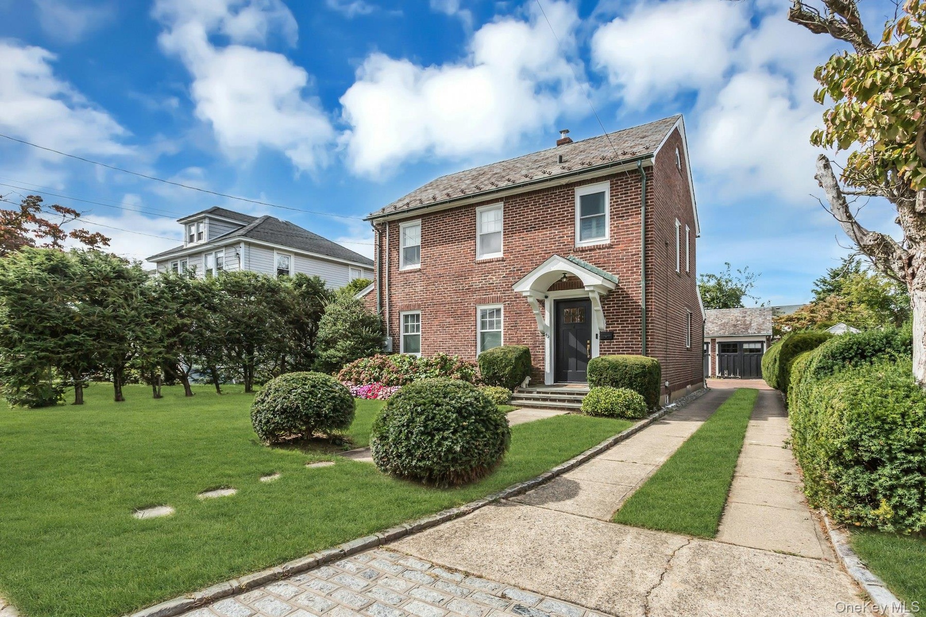 Brick exterior featuring a gabled roof and white window trim, long driveway and det garage